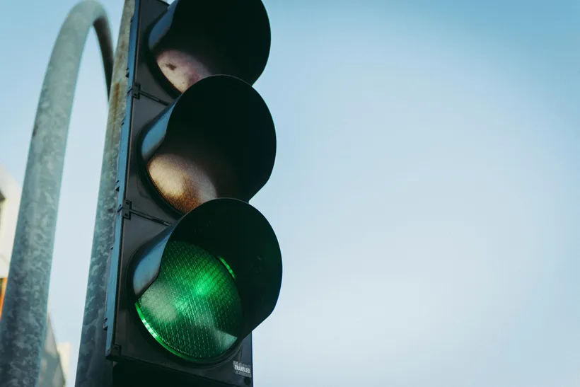 A traffic light showing green against a pale sky